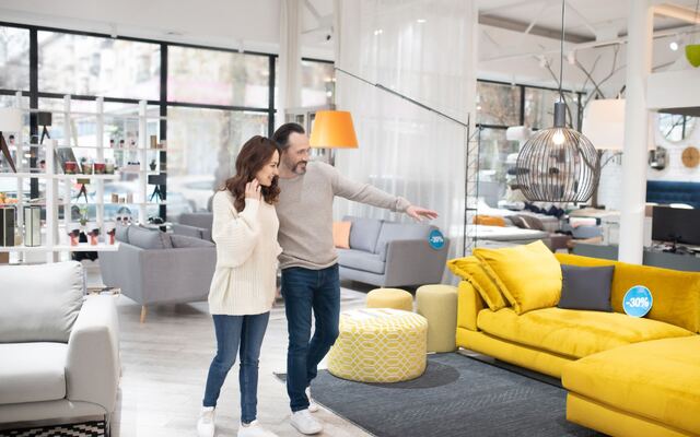 Een stel bekijkt een gele hoekbank in een meubelshowroom