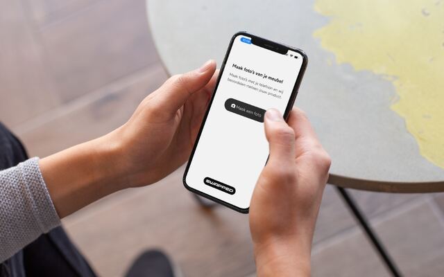 Handen houden een telefoon vast met de vraag om een foto van het meubel te maken