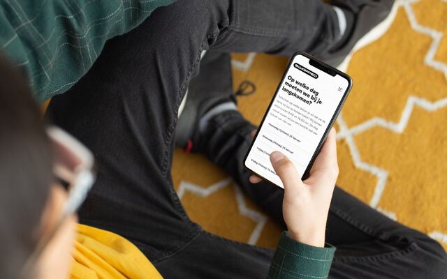 Iemand beantwoordt vragen in de app, zittend op een gele vloer