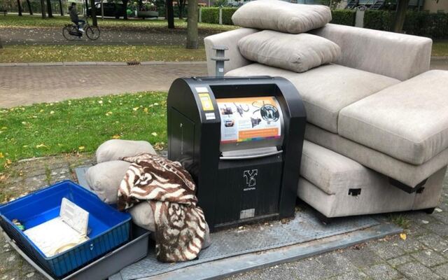 Een hoekbank en kussens naast een ondergrondse container in een park