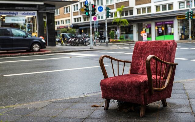 Een rode fauteuil alleen op de stoep in een winkelstraat